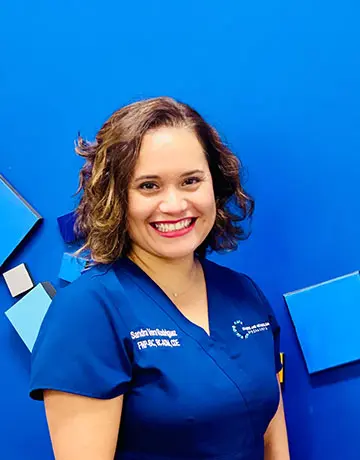 A woman in blue scrubs standing next to a wall.